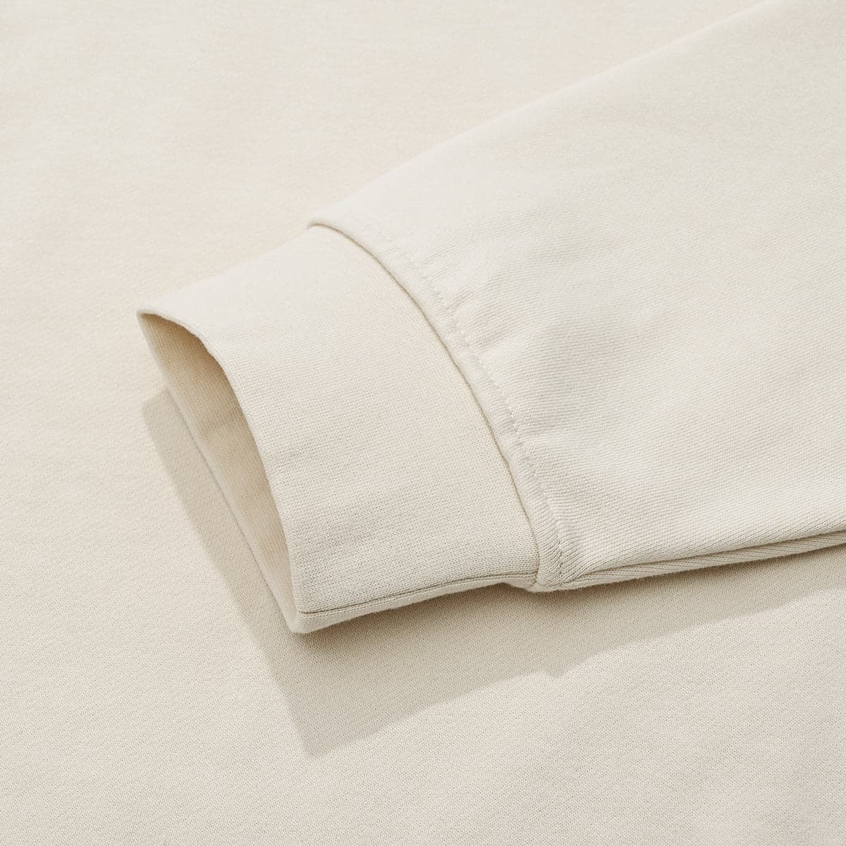 AURACORE graphic half-zip sweatshirt cuff close-up detail in cream cotton